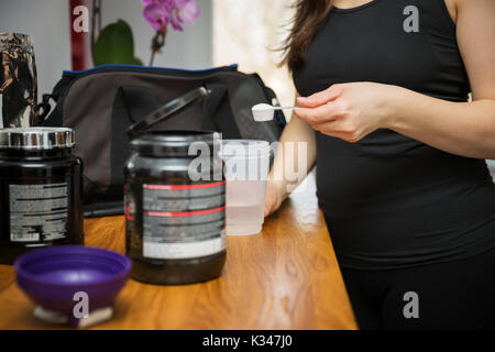 Ein Foto der jungen Frau Vorbereitung einige isotonische Getränk in Ihrer Küche. Stockfoto