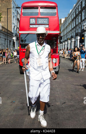 London, Großbritannien. 28 August, 2017. Ein Mann vor einem roten Doppeldeckerbus während der Parade für den Notting Hill Carnival. Stockfoto