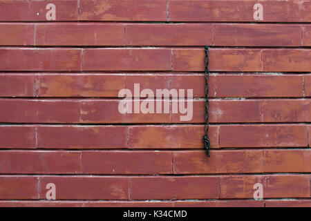 Red brick wall mit hängenden Kette, Nahaufnahme. Stockfoto