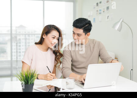 Glückliches junges Paar lesen und analysieren Rechnungen am Tisch sitzen. Junges Paar in ungezwungener diskutieren Hauswirtschaft Stockfoto