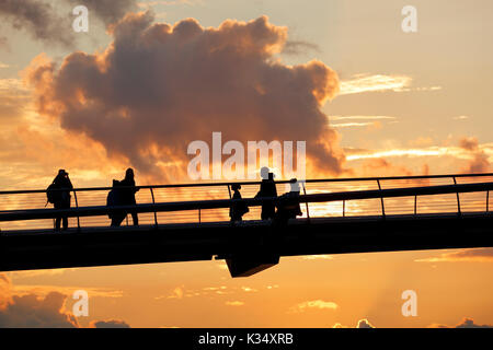 Silhouetten, die über die Millennium Bridge bei Sonnenuntergang, London, der Themse Stockfoto