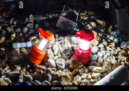 Close-up von zwei roten Camping Laternen beleuchten eines steinigen Strand bei Nacht, nach einem Grill Stockfoto