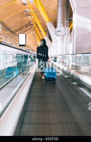 Frau in einem Flughafen zu Fuß schnell in einen Fahrsteig Stockfoto