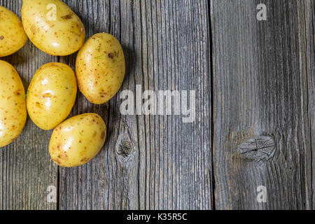 Frische rohe Kartoffeln in einem alten Sack auf Holz- Hintergrund. Freier Platz für Text. Ansicht von oben Stockfoto