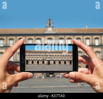 Junge männliche Hände nehmen ein Foto von der Palazzo Reale di Napoli (principal Fassade) auf der Piazza del Plebiscito. Neapel. Kampanien, Italien. Stockfoto