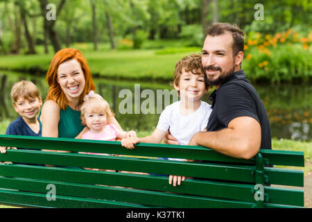 Glückliche Familie sitzt auf der Bank im Park Stockfoto