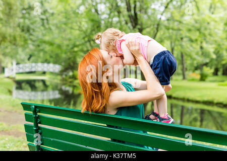 Mutter und ihre kleine Tochter auf einer Parkbank Stockfoto