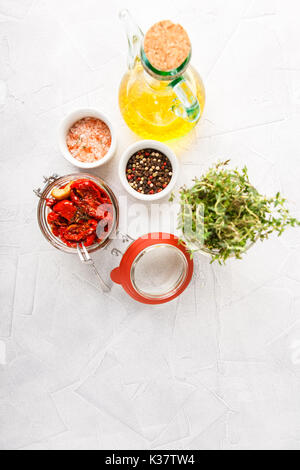 Glas Glas von getrockneten Tomaten, Olivenöl, Thymian und Salz mit rosa Pfeffer. Ansicht von oben Stockfoto