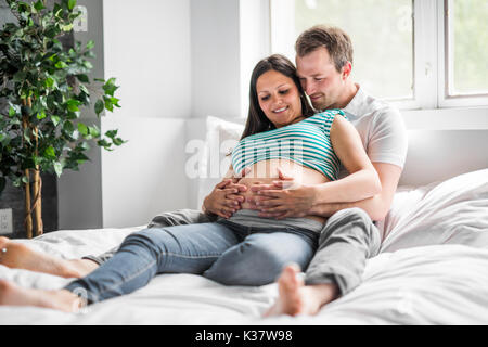 Junge Eltern im Bett erwartet ein kleines Baby, romantische Momente für schwangere Paar Stockfoto