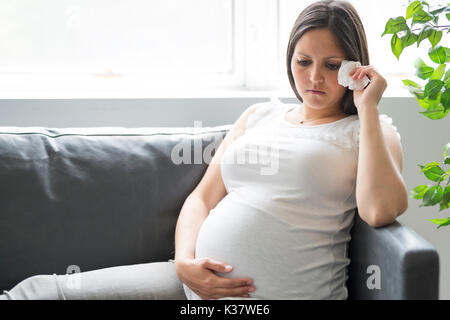 Traurig schwangere Frau auf dem Sofa zu Hause liegen Stockfoto
