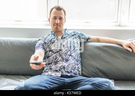 Home, Technologie und Unterhaltung Konzept - lächelnd Mann mit TV-Fernbedienung zu Hause Stockfoto