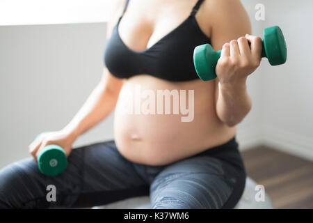 Schwangere Frau training mit Hanteln, aktiv zu bleiben Stockfoto