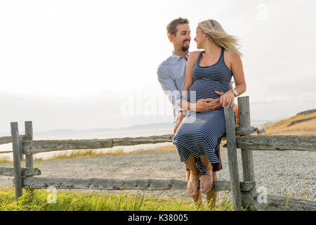 Schwangere Frau am Strand mit Ehemann Spaß Stockfoto