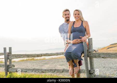 Schwangere Frau am Strand mit Ehemann Spaß Stockfoto