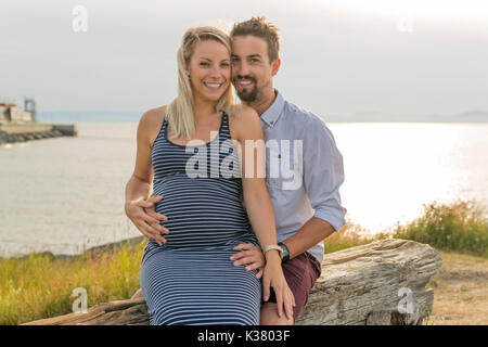 Schwangere Frau am Strand mit Ehemann Spaß Stockfoto