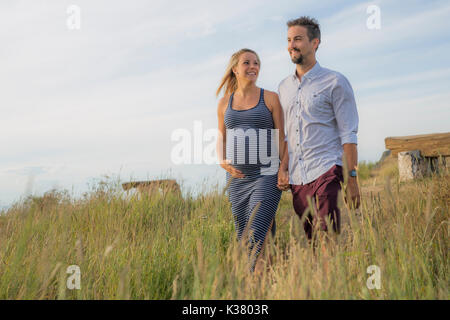 Schwangere Frau am Strand mit Ehemann Spaß Stockfoto