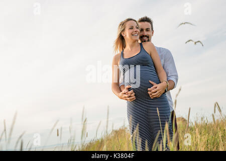 Schwangere Frau am Strand mit Ehemann Spaß Stockfoto