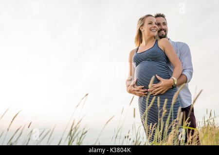Schwangere Frau am Strand mit Ehemann Spaß Stockfoto