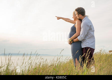Schwangere Frau am Strand mit Ehemann Spaß Stockfoto
