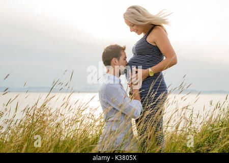 Schwangere Frau am Strand mit Ehemann Spaß Stockfoto