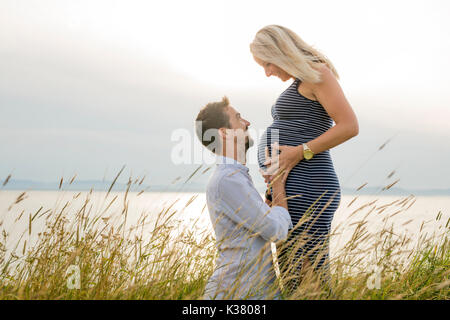 Schwangere Frau am Strand mit Ehemann Spaß Stockfoto
