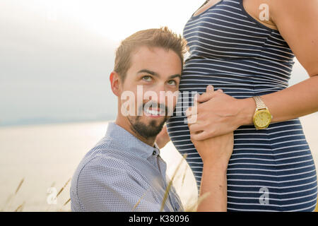 Schwangere Frau am Strand mit Ehemann Spaß Stockfoto