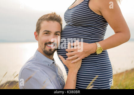 Schwangere Frau am Strand mit Ehemann Spaß Stockfoto