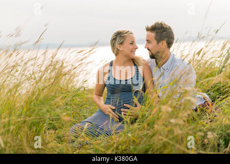 Schwangere Frau am Strand mit Ehemann Spaß Stockfoto