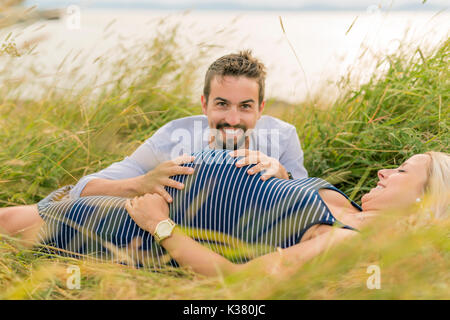 Schwangere Frau am Strand mit Ehemann Spaß Stockfoto