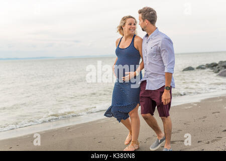 Schwangere Frau am Strand mit Ehemann Spaß Stockfoto