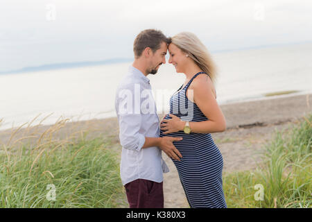 Schwangere Frau am Strand mit Ehemann Spaß Stockfoto