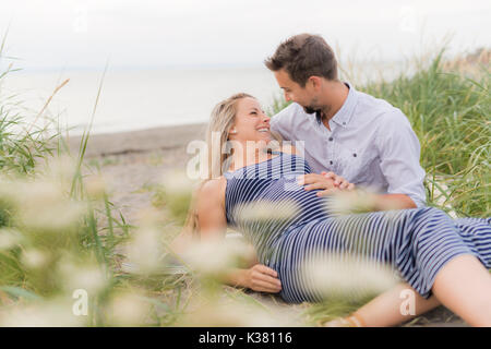Schwangere Frau am Strand mit Ehemann Spaß Stockfoto