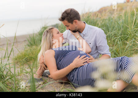 Schwangere Frau am Strand mit Ehemann Spaß Stockfoto