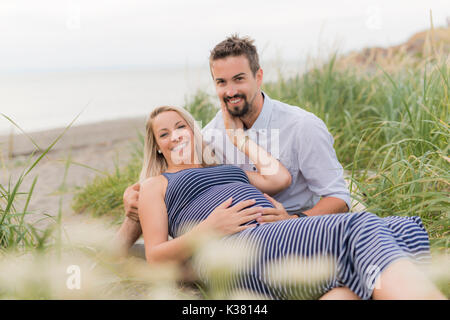 Schwangere Frau am Strand mit Ehemann Spaß Stockfoto