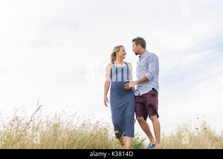 Schwangere Frau am Strand mit Ehemann Spaß Stockfoto
