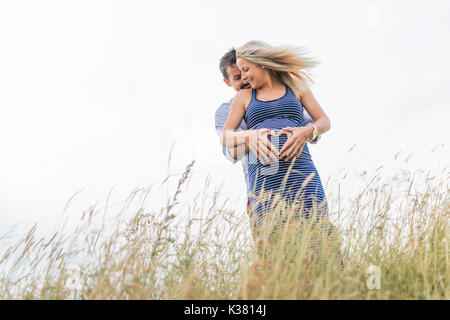 Schwangere Frau am Strand mit Ehemann Spaß Stockfoto