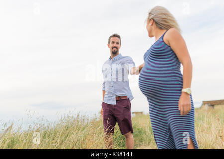 Schwangere Frau am Strand mit Ehemann Spaß Stockfoto