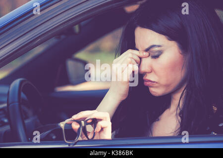 Business Frau mit Kopfschmerzen, die ihre Brille hat eine Haltestelle nach der Fahrt Auto auf Rush hour zu machen. Erschöpft Treiber Konzept. Stockfoto