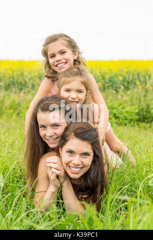 Glückliche Familie, Mutter und Kind Tochter auf gelben Blumen auf die Natur im Sommer umfassen Stockfoto