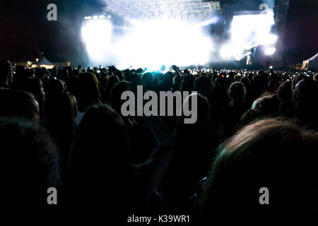 Silhouetten von Konzert Menschenmenge vor der Bühne hell leuchtet. Dunkler Hintergrund, Rauch, Konzert Strahler Stockfoto