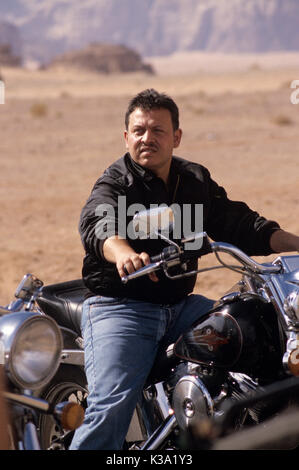 König Abdullah II von Jordanien reiten sein Motorrad im Wadi Rum, während Dreharbeiten Reisedokumentation Jordan: The Royal Tour ca. 2000 Stockfoto