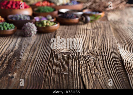 Natürliche Medizin. Kräuter, Beeren und Blumen in Schalen auf hölzernen Tisch. Stockfoto