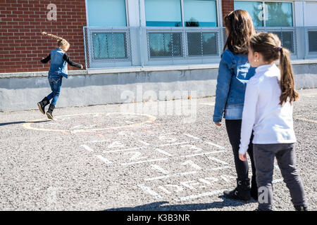 Hopscotch auf dem Schulhof mit Freunden gemeinsam spielen Stockfoto