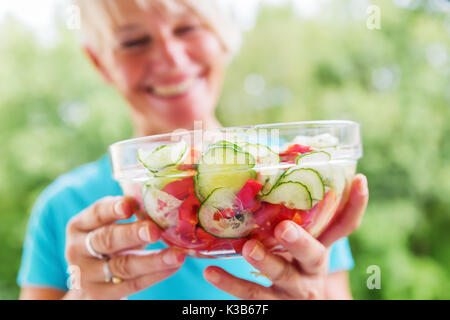 Lächelnd reife Frau hält eine Schüssel mit gesundes Gemüse vor ihrem Gesicht Stockfoto