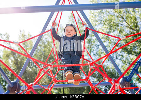 Glückliches Kind Junge, auf dem Spielplatz geklettert Stockfoto