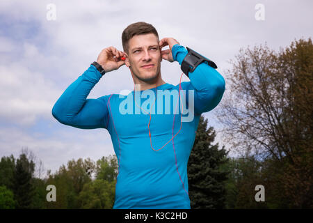 Ein Foto der jungen, gut gebauten Mann in Thermo-aktive T-Shirt. Er der Ohrhörer. Stockfoto