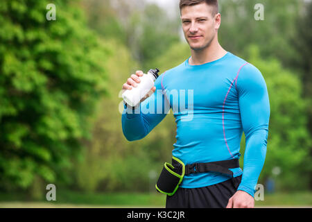 Ein Foto der jungen, gut gebauten Mann im sportlichen Outfit Trinkwasser aus bidon. Stockfoto