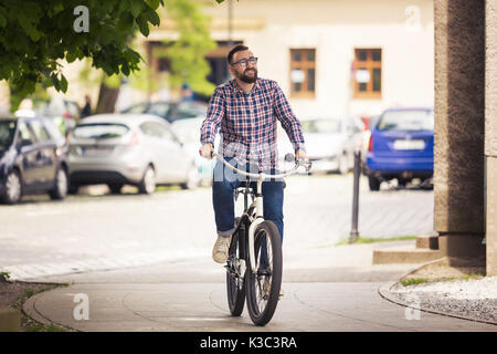 Portrait von jungen trendigen Mann, City Bike auf Pflaster Stockfoto