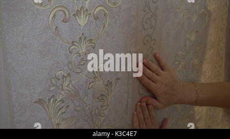 Der Prozess der kleben Tapeten an der Wand, auf dem die Hand des Arbeiters ist glatt Wallpaper. Stockfoto