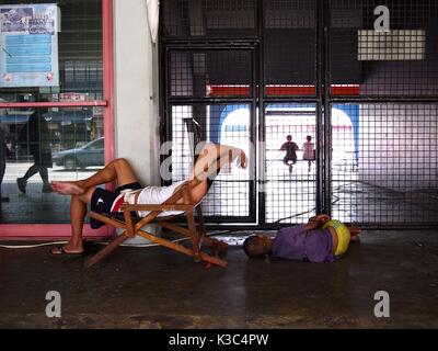 MARIKINA CITY, Philippinen - 28. AUGUST 2017: ein Mann und eine junge Schlafen auf dem Gehsteig außerhalb ein Sportstadion in Marikina City, Philippinen Stockfoto